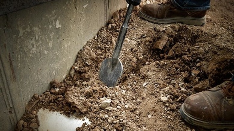 Person digging in the dirt with the clay spade
