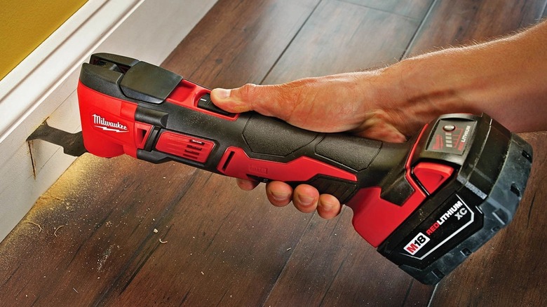 Individual cutting through baseboards with the multitool