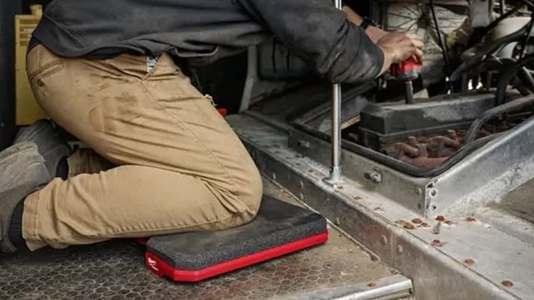 Man kneeling working on his knees while working on equipment