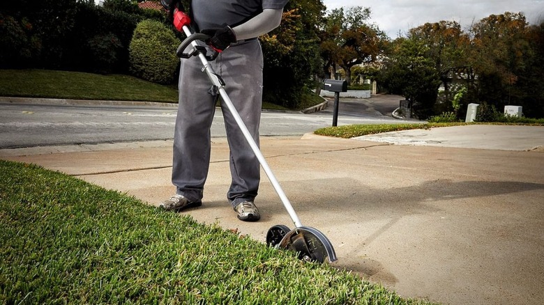 Man using an edger along side a driveway border