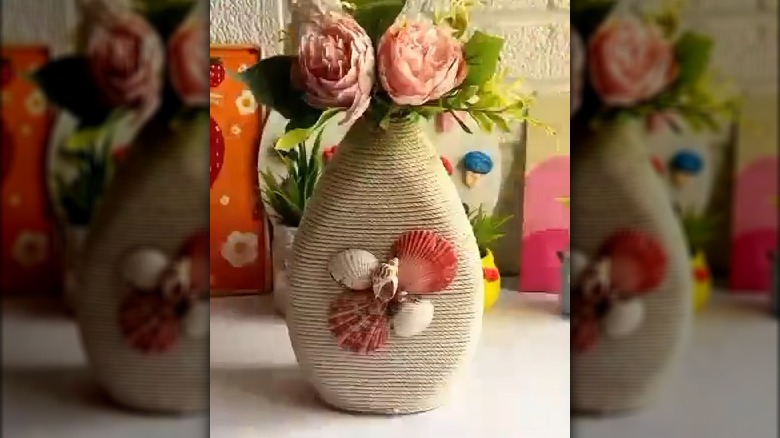 Pink flowers in vase wrapped with twine and embellished with seashells
