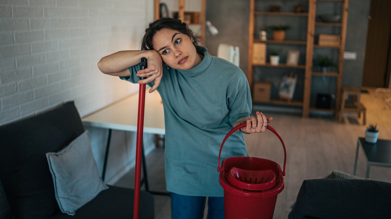 A stressed woman holding a mop