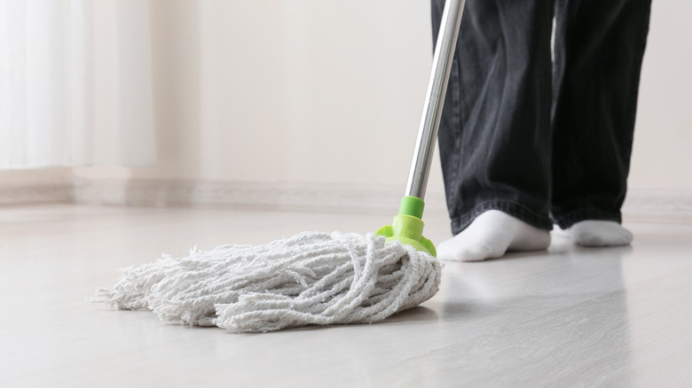 Person holding dry string mop on light flooring