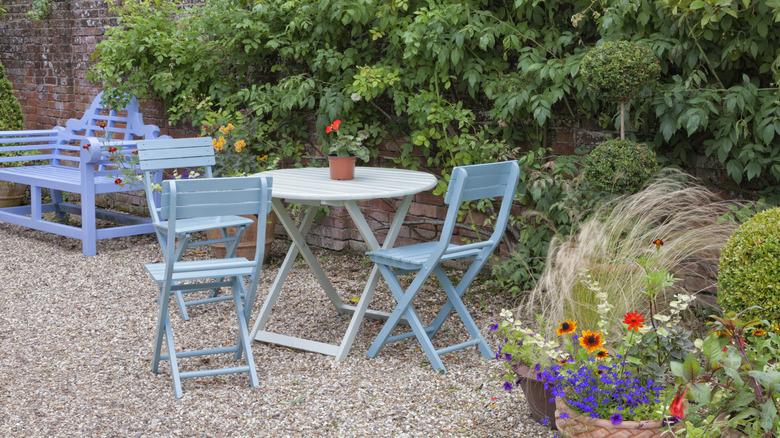 A gravel patio features blue painted furniture and floral planters