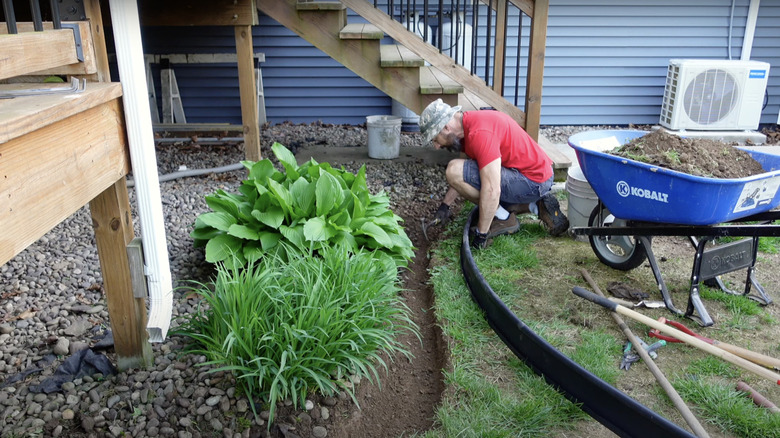 man installing plastic border around garden
