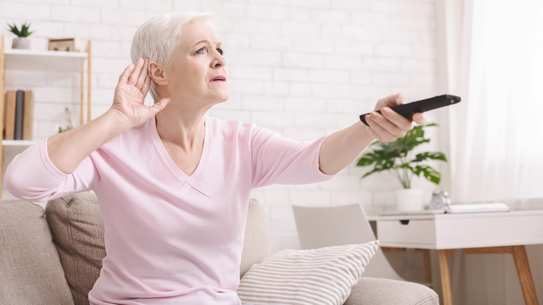 woman cupping ear holding remote