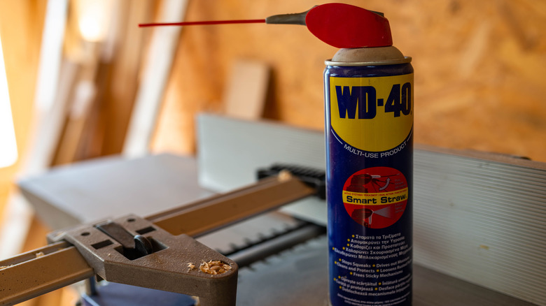 A can of WD-40 with a wood planer in the background, coated in sawdust