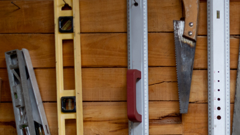 A large collection of clean and well-maintained tools hung in an orderly fashion on a shed wall