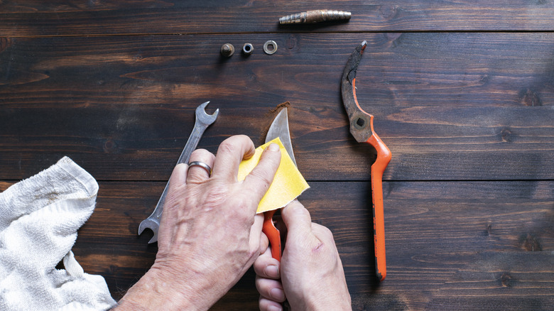 Close-up shot of a person sanding rust from a hand tool