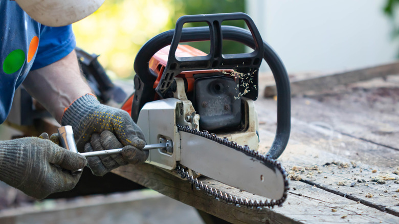 A person repairing a chainsaw with a loose chain