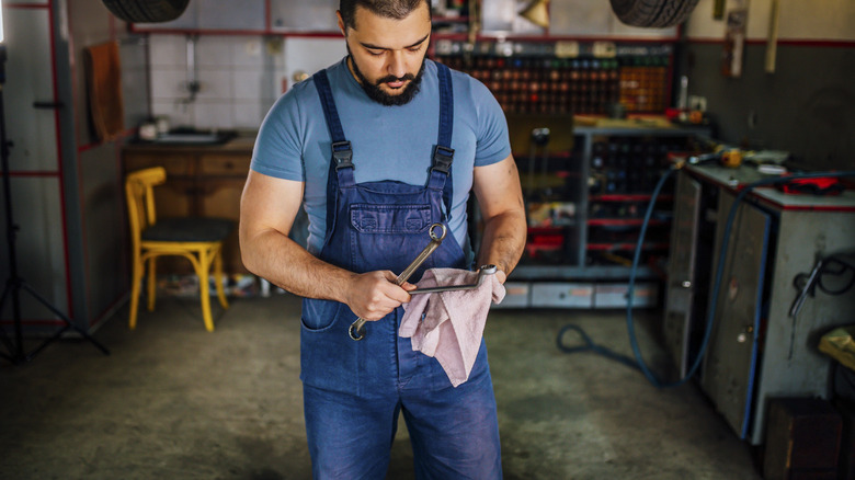 A man cleaning a tool with a cloth