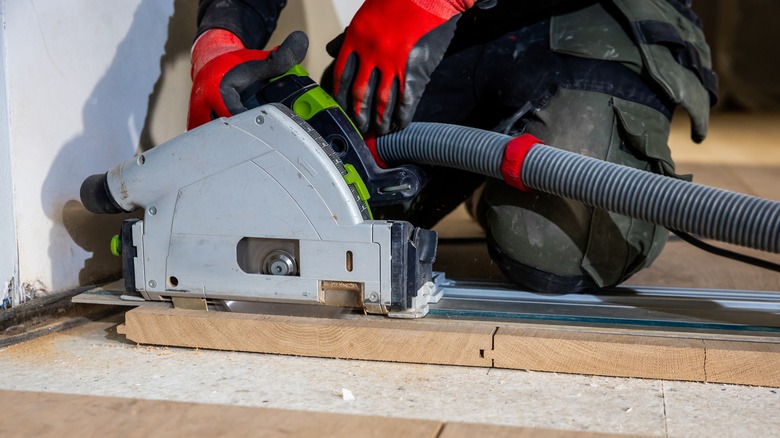 Person wearing red gloves cutting wood with speciality saw