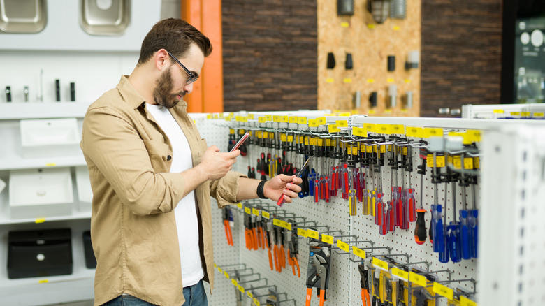 Person looking at a cell phone while shopping for tools