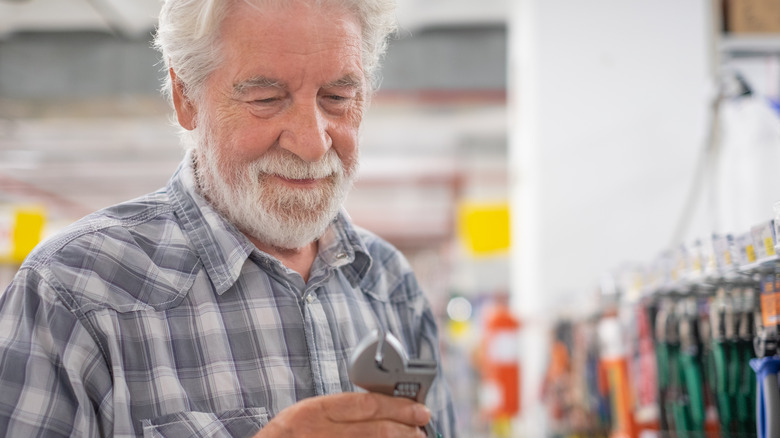 Senior man buying a wrench at a hardware store