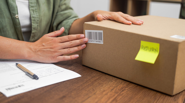 Person placing a barcode on a cardboard box to be returned to a store