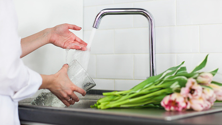 Close-up of a person cleaning a vase, with flowers laying on the side