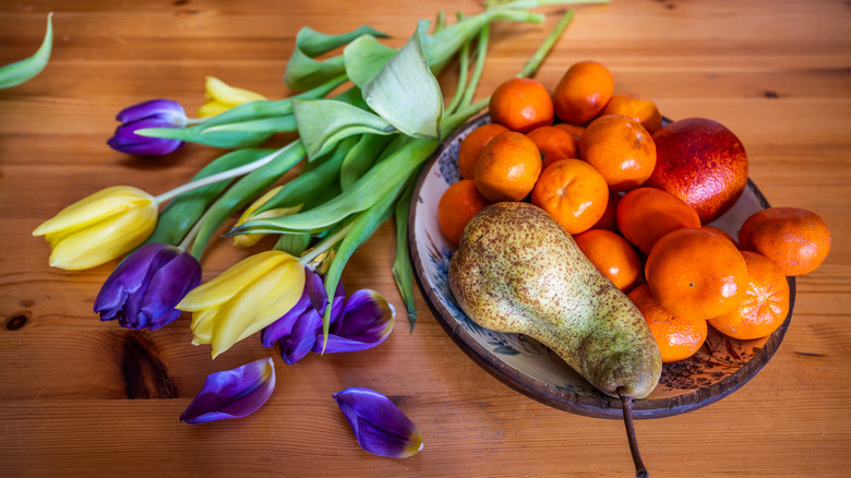 Flowers laid on a table next to a fruit bowl