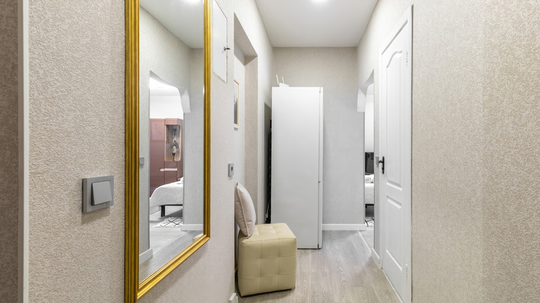A small entryway with bare walls and mirror in the wrong spot