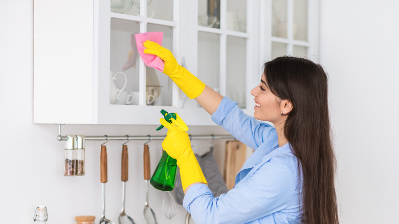 Woman cleaning kitchen cabinets