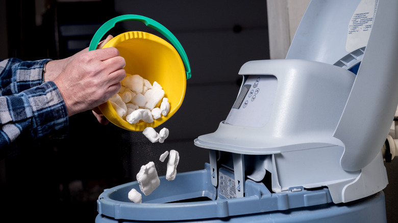 A person adding salt to a water softener