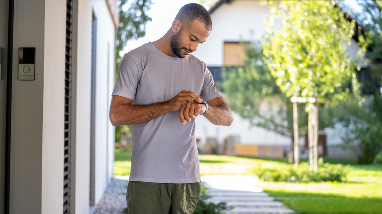 A man looks at his watch as he walks into his garden.