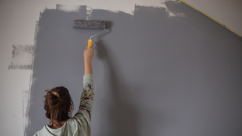 woman painting wall gray