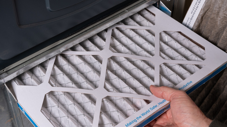 hand placing a new air filter in a HVAC system
