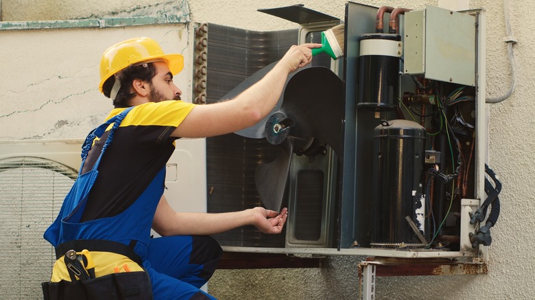 Professional removing dust from a blower fan on HVAC system