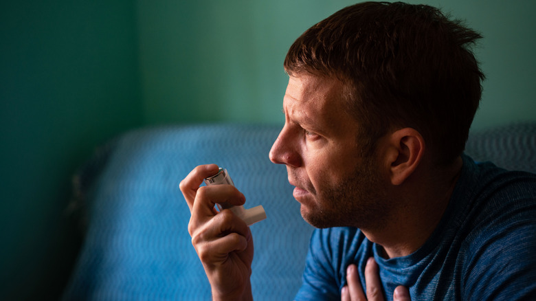 man holding an inhaler indoors