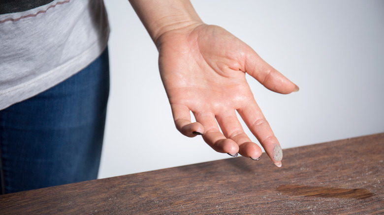 dust from table being rubbed off by a finger