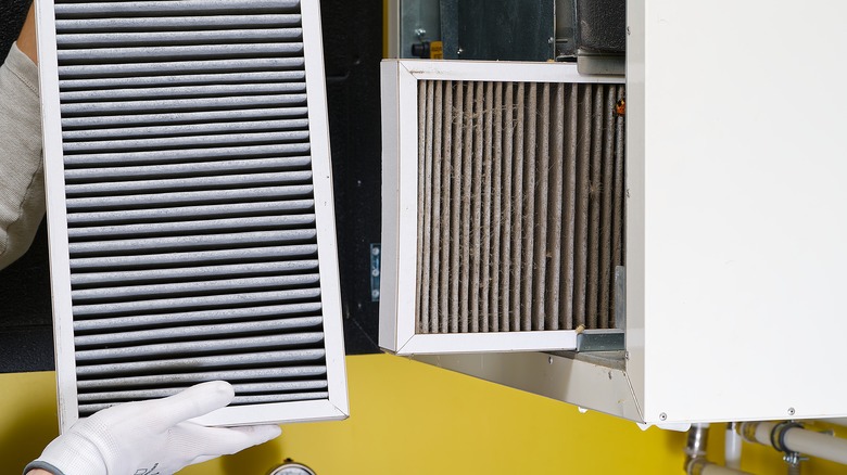 person about to replace an old dusty hvac air filter with a new one