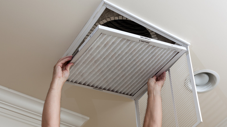 person reaching up to maintain air filter