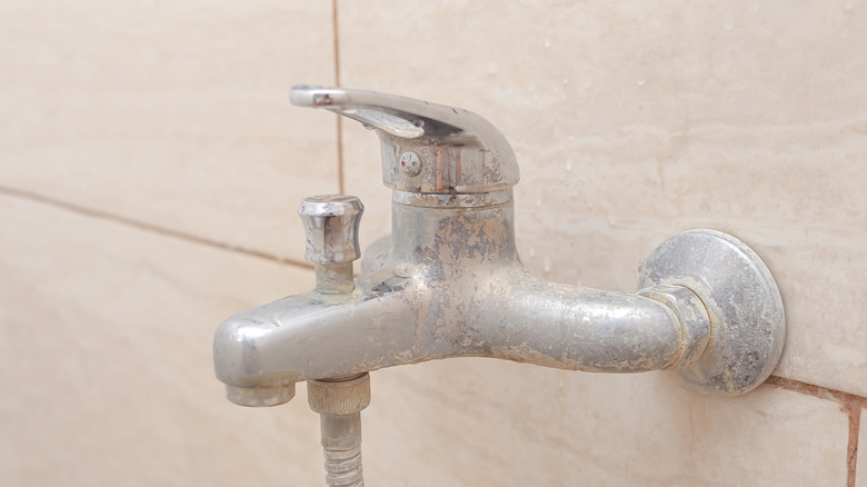 Limescale buildup on a faucet with tile in the background