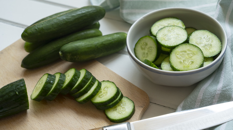 Sliced cucumber with whole ones and a knife