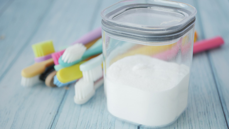 pot of baking soda with pile of toothbrushes