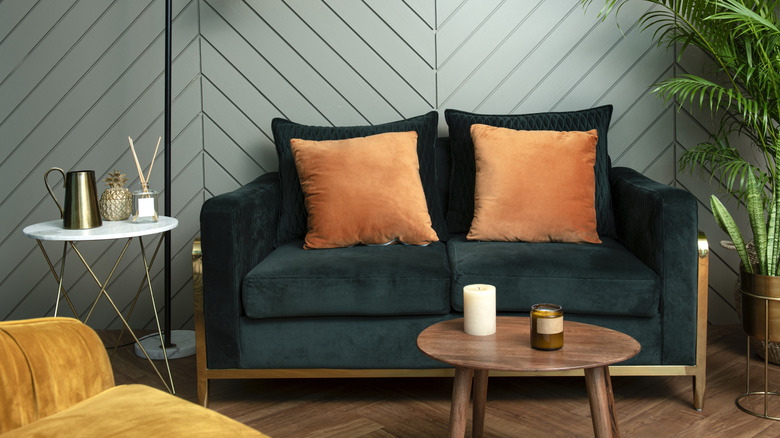 a velvet green loveseat in a retro style room