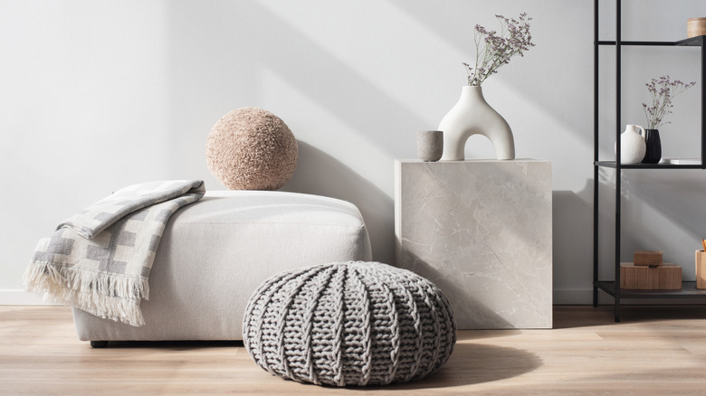 a wall in a modern room with a gray pouf and ottoman
