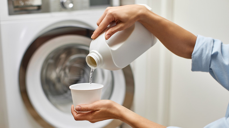 Woman pouring bleach into load of laundry