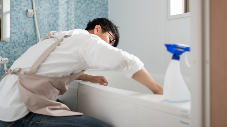 Man cleaning the tub in modern bathroom