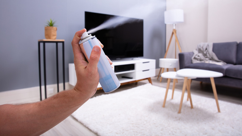 Spraying air freshener into carpeted room