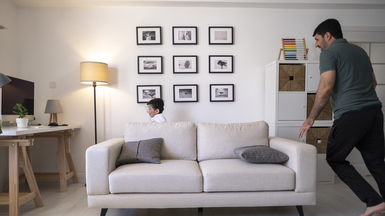 Framed photos arranged in a grid pattern on a wall behind a sofa
