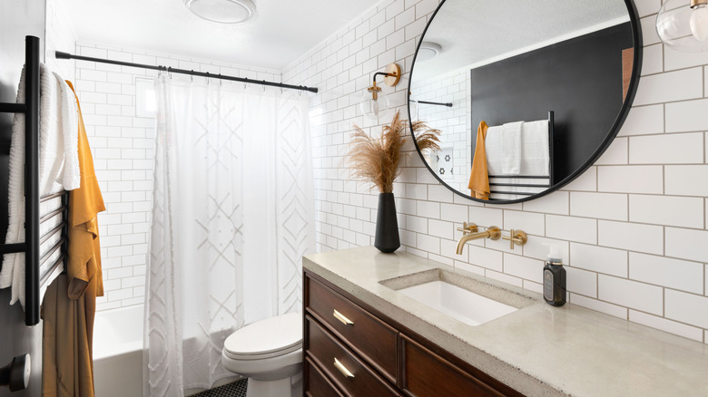 Clean white bathroom with a sheer white cotton shower curtain hanging over the bathtub.