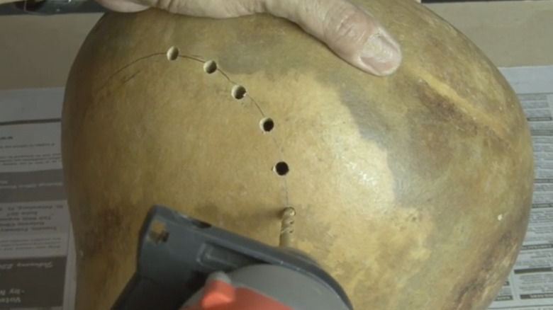 A person drilling into a gourd lantern