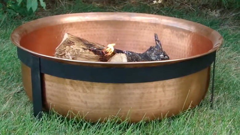 A copper bowl fire pit in a yard