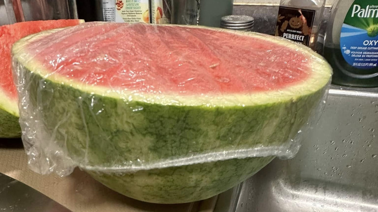 Cut watermelon is covered with a shower cap.