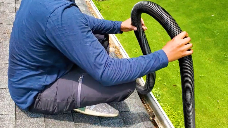 Person placing shop vac hose in gutter