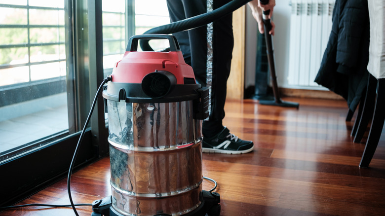 Person cleaning wood floors with industrial shop vac