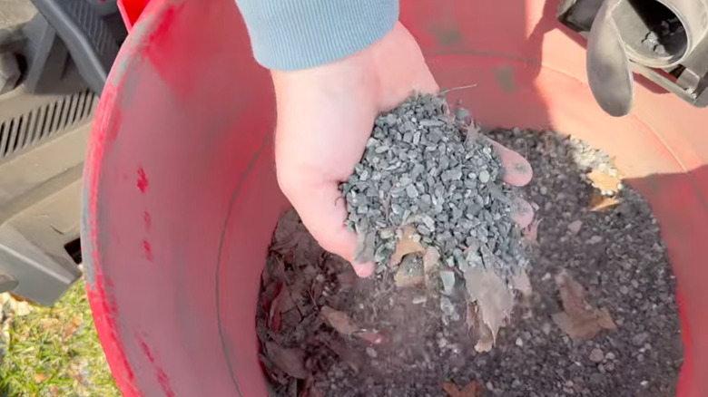 Hand scooping small stones from shop vac canister