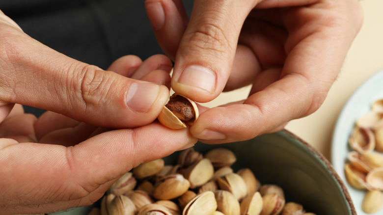 A person peeling pistachios and reserving the shells