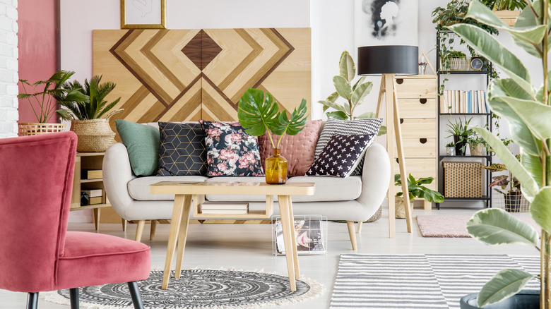 A bold living room with printed rugs, throw pillows, and a large art installation.